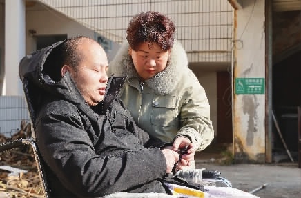 1月11日,肖慧君推著譚燦江在小院裡曬太陽. 何佳潔 攝